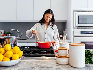 Reliable heating and cooling for total home comfort Homeowner enjoying consistent indoor comfort while cooking in a climate-controlled home