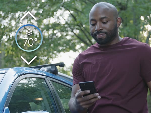Control your home comfort remotely with a smart thermostat Homeowner adjusting a smart thermostat remotely from his phone for energy-efficient home comfort