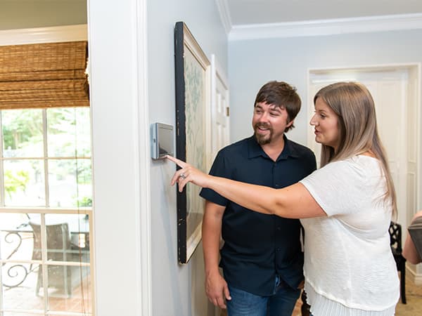 Couple reviewing settings on a new smart thermostat for customized home comfort Couple reviewing settings on a new smart thermostat for customized home comfort