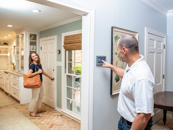 Smart Thermostat Installation & Energy Savings Homeowner adjusting smart thermostat before leaving home in Granite Bay, CA